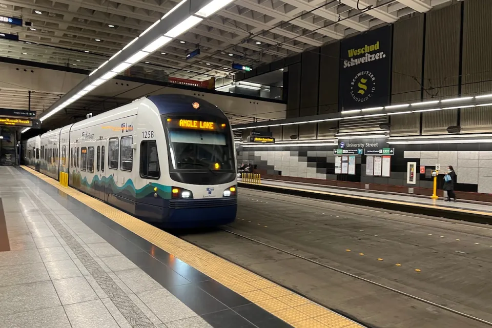 White and blue Seattle Link light rail train pulling into station in Seattle, Washington.